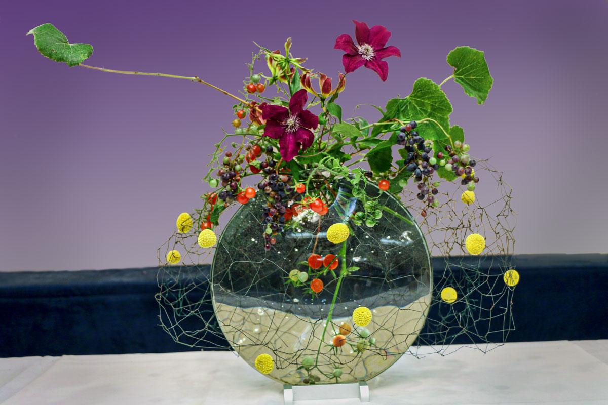 A floral arrangement that uses a clear glass spherical vase, with an assortment of wildflowers emerging from the top